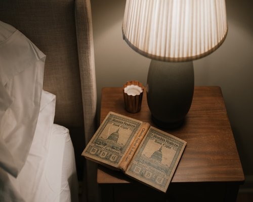 An open book illuminated by a warm reading lamp on a nightstand