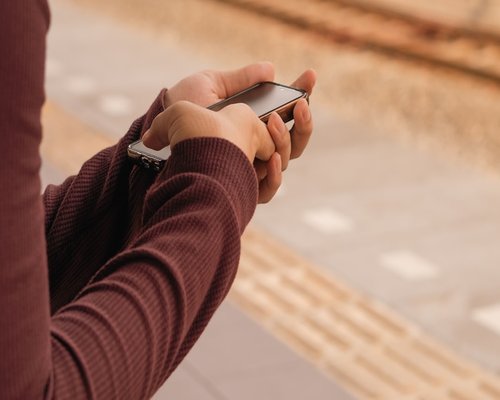 Person holding a smartphone at a comfortable distance while commuting